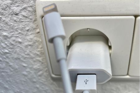 Ein iPhone-Ladegerät mit Kabel in einer Steckdose.