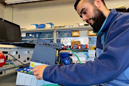 Ein Auszubildender im Bereich Elektrotechnik sitzt an einem Tisch in der Lehrwerkstatt.